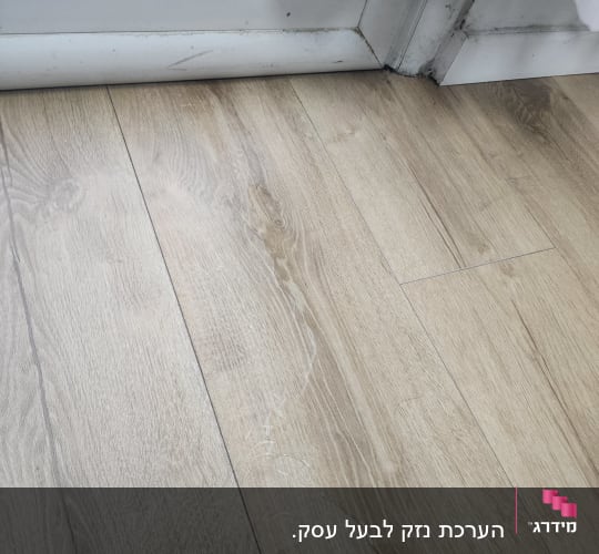 רצפת עץ עם סימני מים ליד דלת זכוכית
